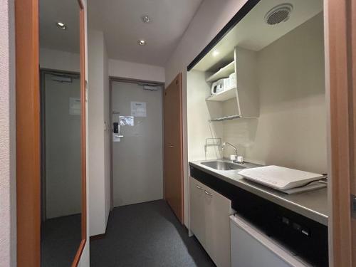 a small kitchen with a sink and a bathroom at TOMAレジデンスホテル TOMA Residence Hotel in Kure
