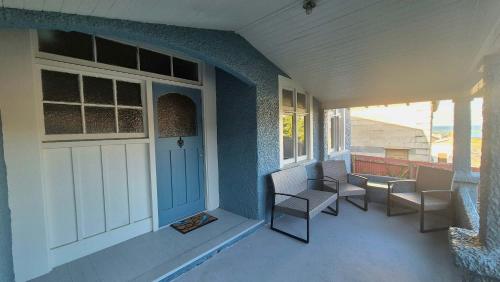 a porch with chairs and a door on a house at Welcome To Wansbeck in Oamaru