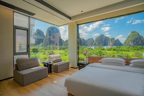 a bedroom with a bed and a large window at 桂林阳朔良宿 LS Hotel Liangsu Yangshuo in Yangshuo