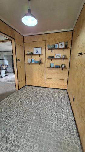 a room with a wall with shelves and a rug at Welcome To Wansbeck in Oamaru