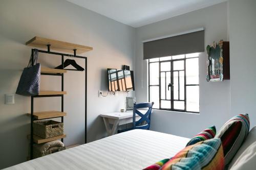 a bedroom with a bed and a desk and a window at La Palomilla Bed & Breakfast in Mexico City