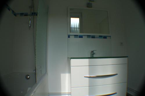 ein weißes Badezimmer mit einem Waschbecken und einem Spiegel in der Unterkunft Résidence du Château Lublin in La Bresse