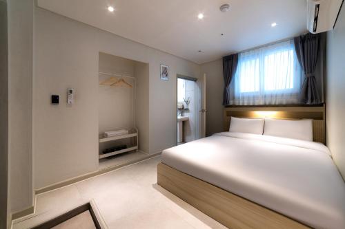 a bedroom with a large white bed and a window at BigBoxStay Myeongdong in Seoul