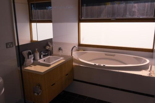 a bathroom with a tub and a sink and a window at Camelot in Kingscote