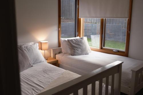 a bedroom with two beds and a window at Camelot in Kingscote