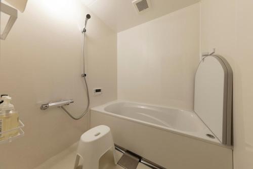 a white bathroom with a tub and a toilet at nikko nagomi 和み in Nikko