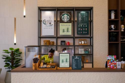 a woman standing behind a counter in a coffee shop at D Varee Jomtien Beach, Pattaya in Jomtien Beach