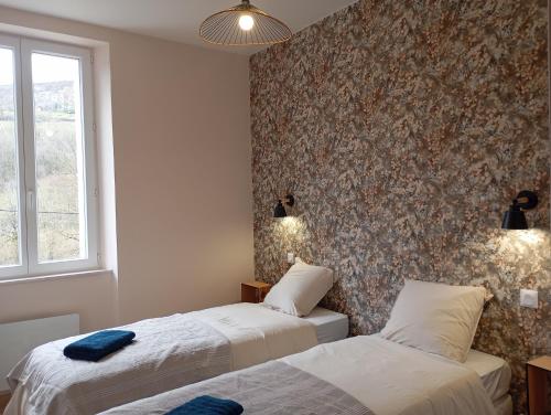 two beds in a room with a wall at Gite La maison du gardien in Marcillac-Vallon