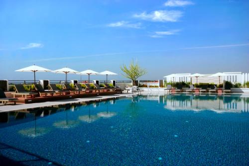 a large swimming pool with chairs and umbrellas at Kameo Grand Hotel & Serviced Apartment, Rayong in Rayong