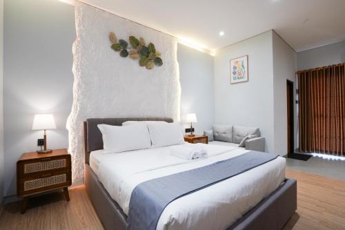 a bedroom with a large white bed and a chair at The Lavana Infinity Jogja Villa in Salakan