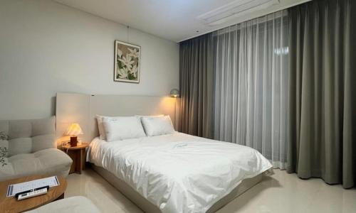 a bedroom with a white bed and a window at Yeonsan The Stay in Busan