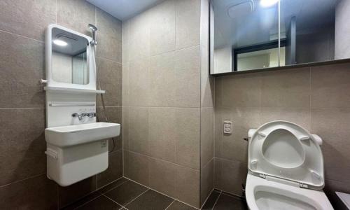 a bathroom with a toilet and a sink and a mirror at Yeonsan The Stay in Busan