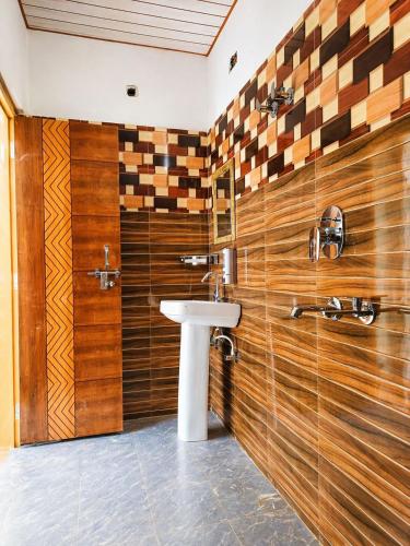 a bathroom with a sink and wooden wall at Athiti Devo Bhava in Chakrāta