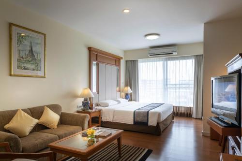 a hotel room with a bed and a television at Kameo Grand Hotel & Serviced Apartment, Rayong in Rayong