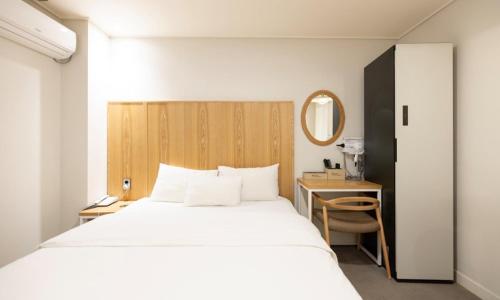 a bedroom with a bed and a desk with a mirror at Cheongju Hotel Dictionary in Cheongju