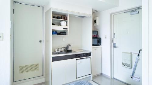 a kitchen with white cabinets and a sink at 9Stay川崎 in Kawasaki