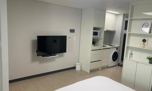 a white room with a flat screen tv on a wall at Myeongga Ubleth Hotel in Yeosu