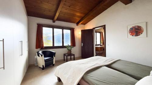 a bedroom with a bed and a chair and a window at La Finestra sul lago in Brissago