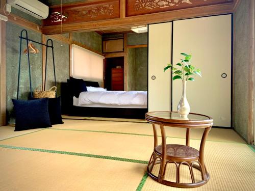 a bedroom with a bed and a table with a vase on it at 宇佐神宮近く- 神さまと仏さまと kamisama to hotokesama to in Nagasu