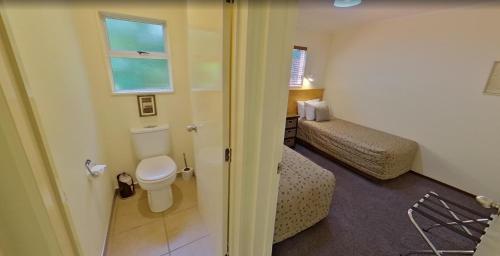 a small bathroom with a toilet and a window at Creel Lodge in Turangi