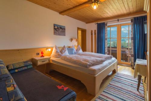 a bedroom with a bed and a couch and a window at Lindenhof in Kitzbühel