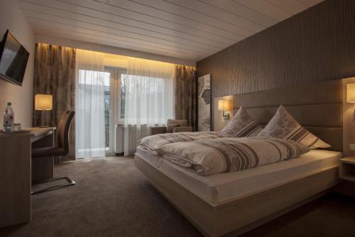 - une chambre avec un grand lit et un bureau dans l'établissement Landhaus Kramer, à Willingen