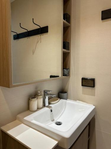 a bathroom with a white sink and a mirror at Avrora Laguna Residences Sky Park in Ban Thalat Choeng Thale