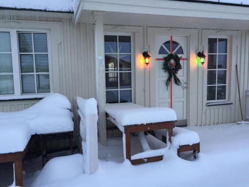 a house covered in snow with two benches and a wreath at The White House in Reykholt