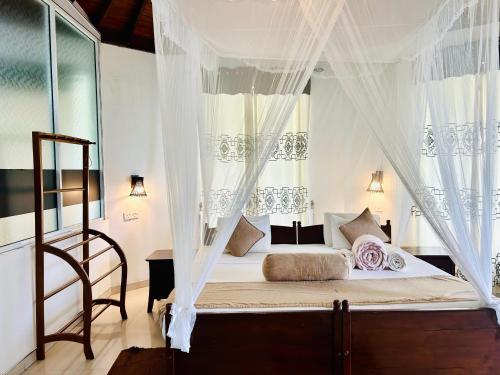 a bedroom with a canopy bed with curtains at Hotel Ella`s Edge in Ella