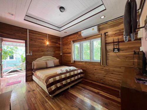 a bedroom with a bed in a room with wooden walls at Ariya Garden Home in Chumphon