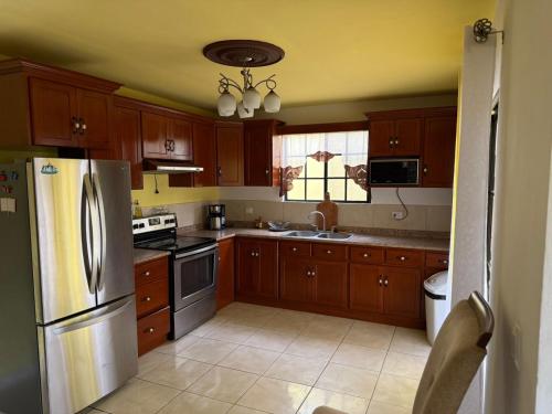 a kitchen with wooden cabinets and a stainless steel refrigerator at Aloft Alvarado in Siguatepeque
