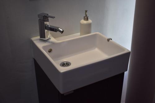 lavabo blanco en el baño con dispensador de jabón en Hostal MiMi Las Ramblas, en Barcelona