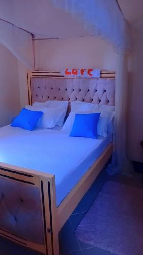 a bedroom with a large bed with blue pillows at Pebs one bedroom apartment in Mombasa