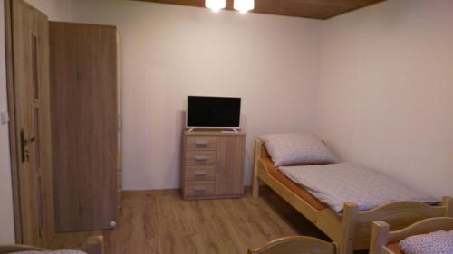 1 dormitorio con 2 camas y un tocador con TV en Podřipská Farma, en Roudnice nad Labem