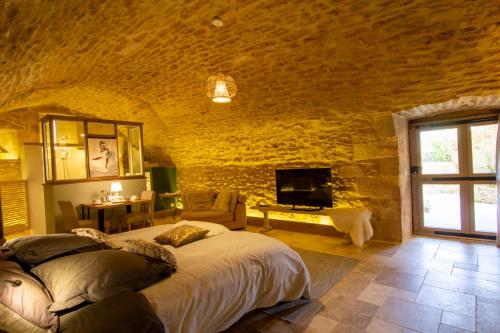 a bedroom with a large bed in a stone wall at Le Clos de la Tour in Sainte-Nathalène
