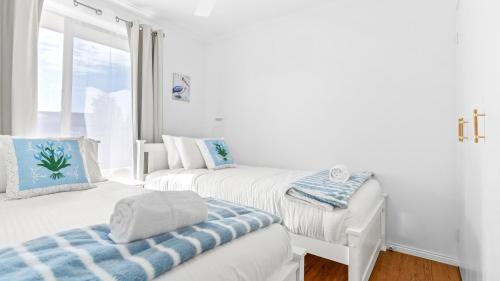 a white room with two beds and a window at Keyside Escape in Forster