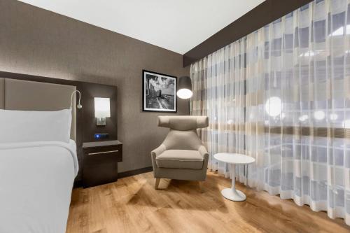 a bedroom with a bed and a chair and a window at Radisson Hotel St Louis Downtown Convention Center in Saint Louis
