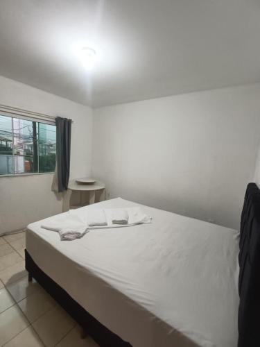 a white bed in a room with a window at Apartamento simples com vista para a praça in Palhoça