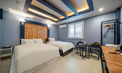 a bedroom with two beds and a table and a desk at 충주 호텔 발리 in Chungju