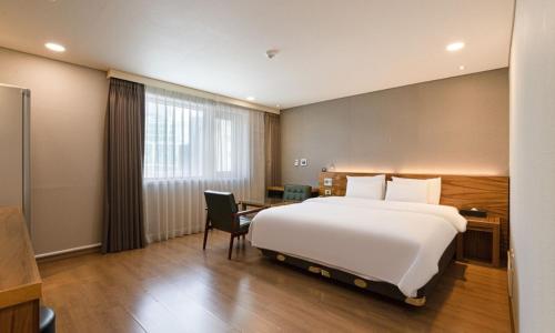 a hotel room with a large white bed and a desk at Anyang CNC Hotel in Anyang