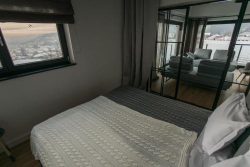 a bedroom with a bed and a window with a couch at The Pines Boutique Villa in Braşov