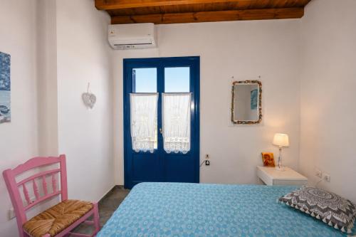 a bedroom with a blue door and a pink chair at Tzados Sunny Villa in Kariá
