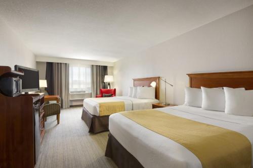 a hotel room with two beds and a television at Country Inn & Suites by Radisson, Sidney, NE in Sidney