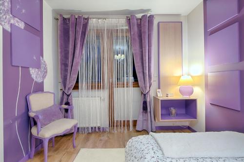 a purple bedroom with a bed and a chair at Blisko Wszędzie in Zakopane