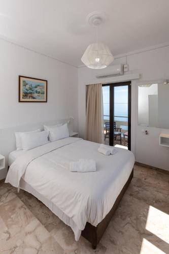 a bedroom with a large white bed with a view of the ocean at Argo Rooms-Papadakis in Kissamos