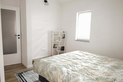 a white bedroom with a bed and a window at AG Apartmans in Gornji Vakuf