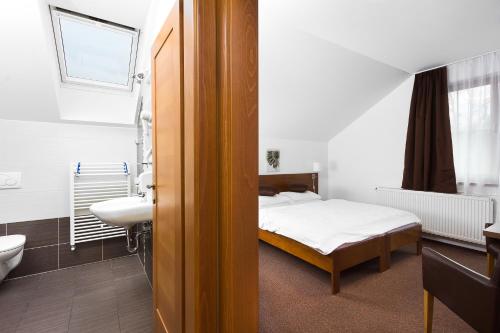 1 dormitorio con cama, lavabo y baño en Penzion Chopok - Apartments, en Liptovský Mikuláš