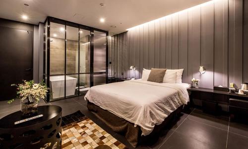a bedroom with a large bed and a bathroom at Hotel The May in Namyangju