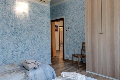 a bedroom with blue wallpaper with a bed and a chair at Guest House Fantaccini con Piscina in Pelago
