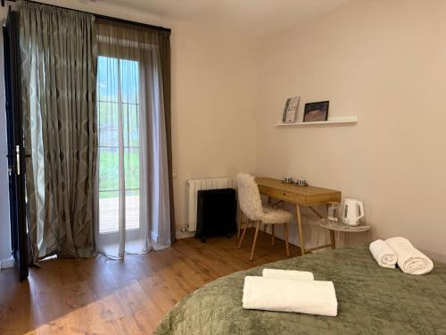 a bedroom with a bed and a desk and a window at Savanna Guest House in Dedoplis Tskaro